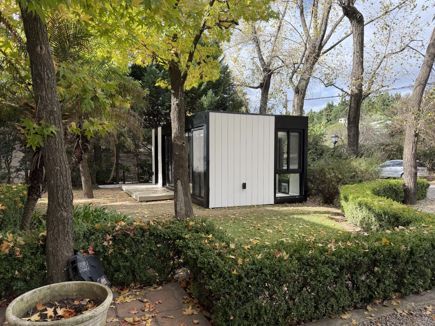 Módulo OFFIS blanco y negro en jardín con árboles