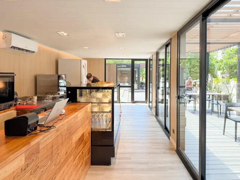 Interior cafetería IRSA con mostrador de madera y ventanales